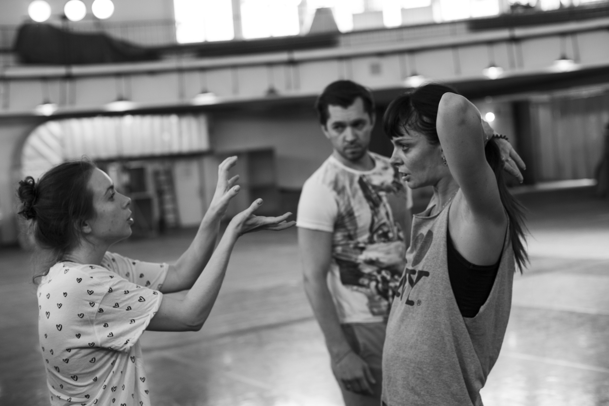 A couple of dancers watch and listen as choreographer gives them pointers.