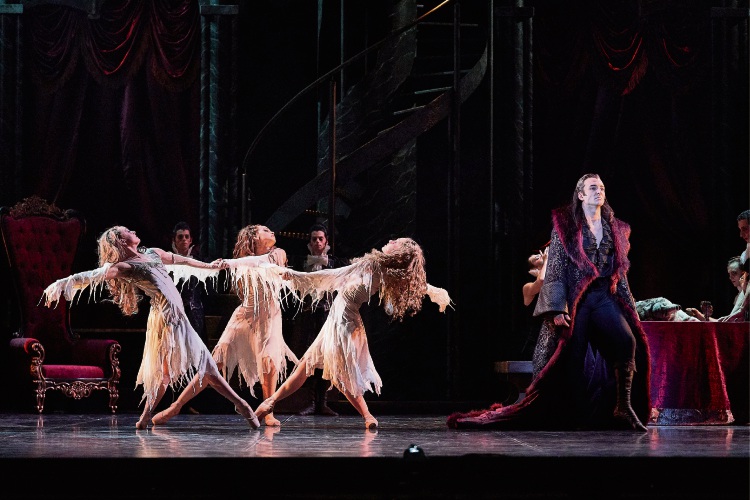 Stage shot with three female dancers on the left and male dancer as Dracula on the right