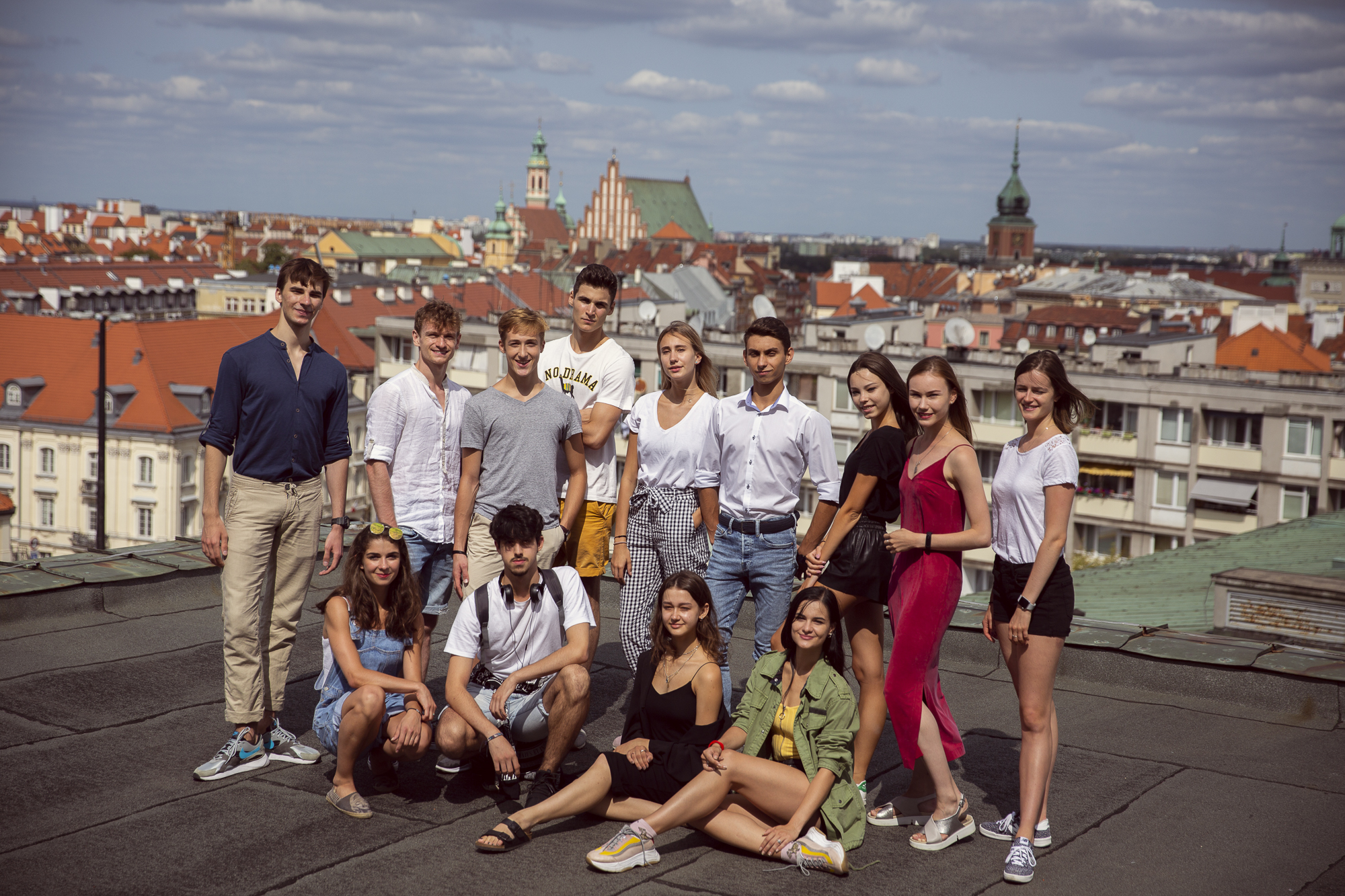 Grupa młodych ludzi na balkonie z panoramą miasta w tle