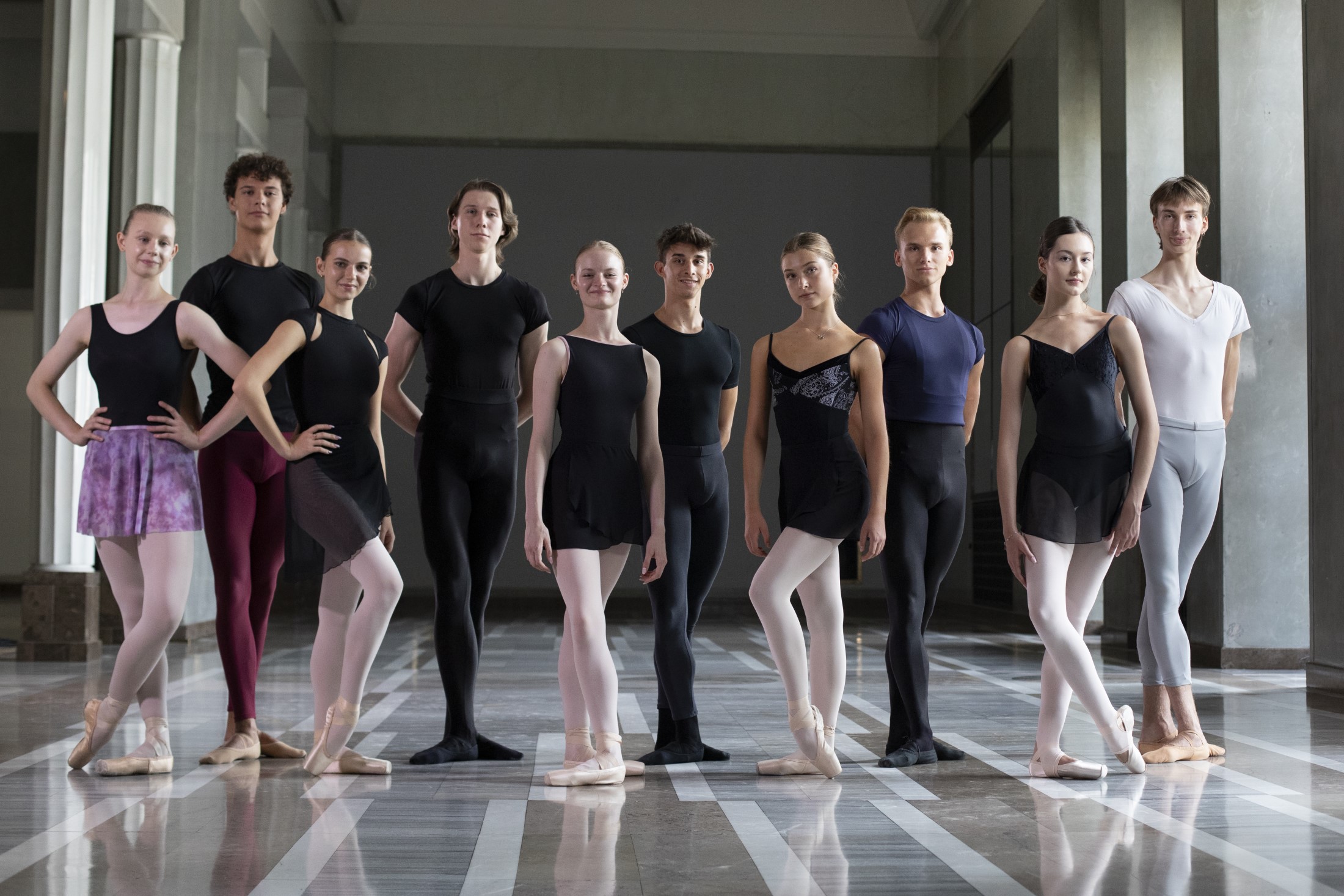 Ten young ballet dancers in dance poses in the lobby of the Polish National Opera