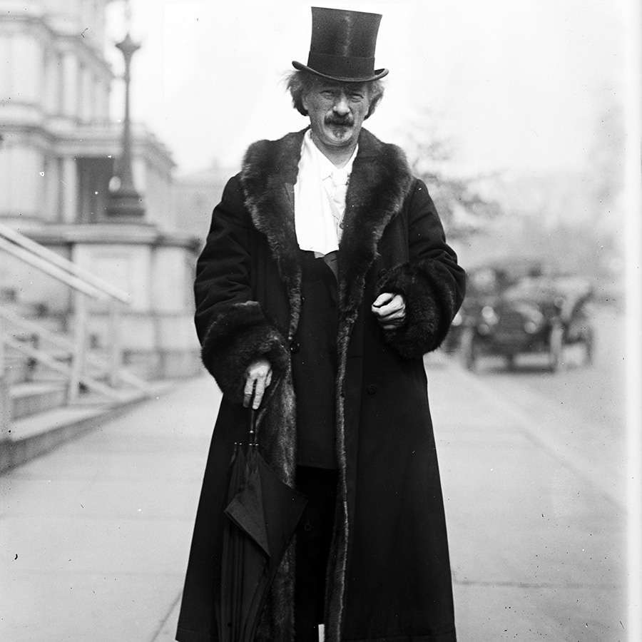 Paderewski in a street wearing in a top hat and fur-trimmed coat